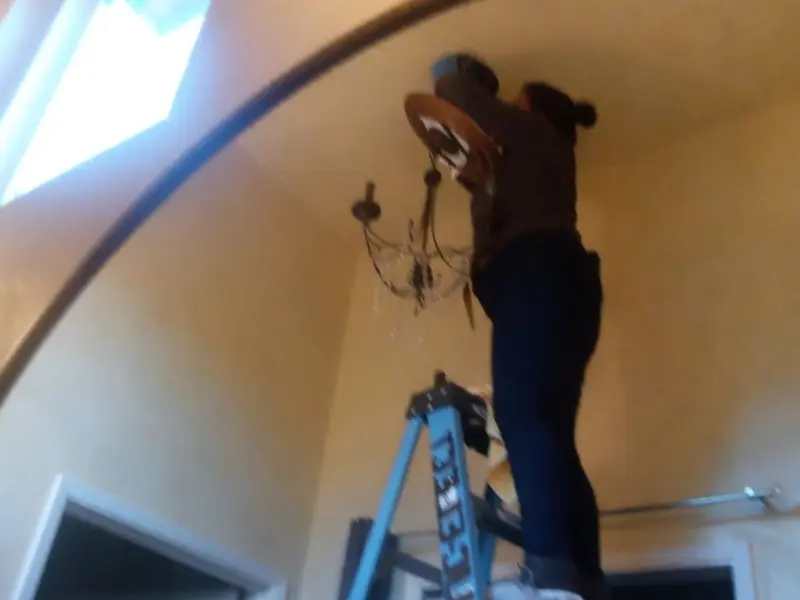 Electrician installing a chandelier in a Estero residence